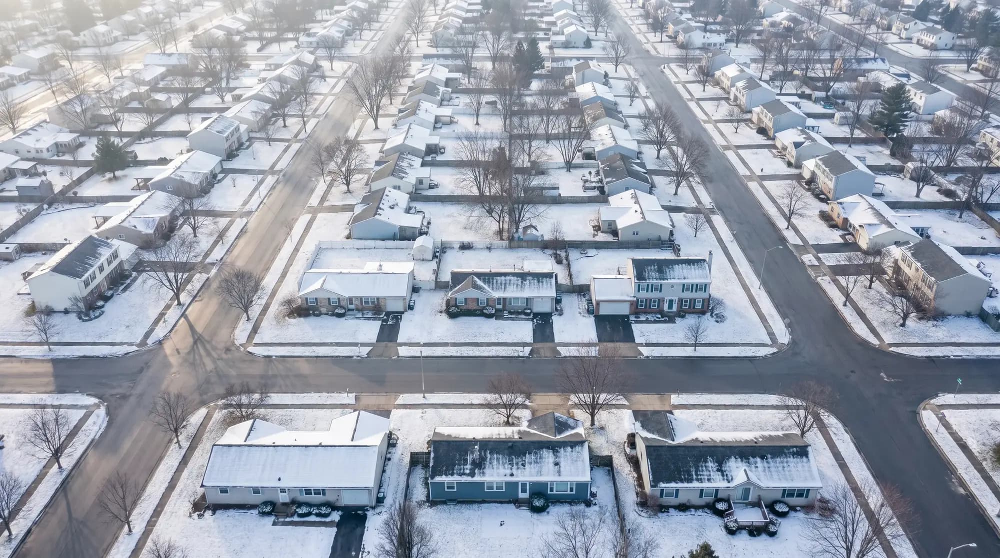 Snow-dusted rooftops across an eastern Erie County neighborhood at dusk, illustrative