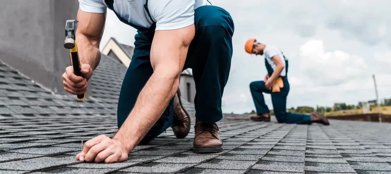 A Mann Roofing roofer hand-nailing shingle courses on a Buffalo area roof